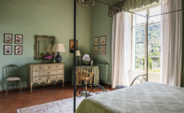 Cozy bedroom featuring green walls, large windows with scenic views, a vintage dresser, and elegant decor, creating a serene and inviting atmosphere.
