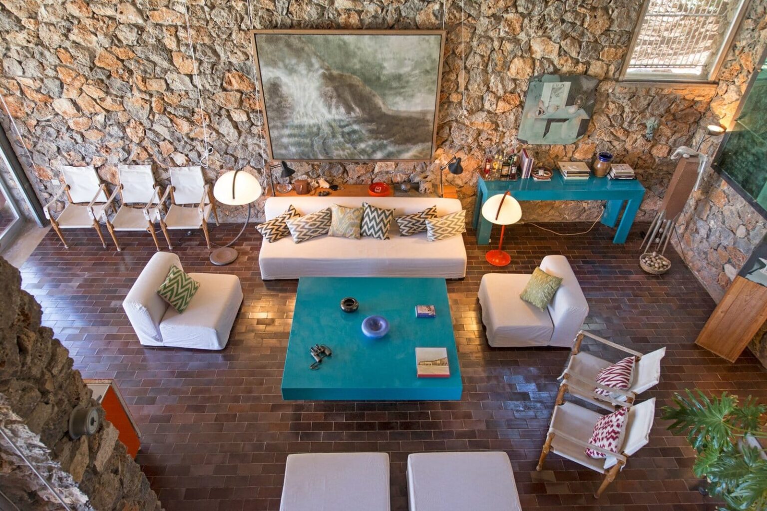 Stylish living room featuring a stone wall, modern furniture, and a vibrant turquoise coffee table, with natural light illuminating the space. | Only on SopranoVillas