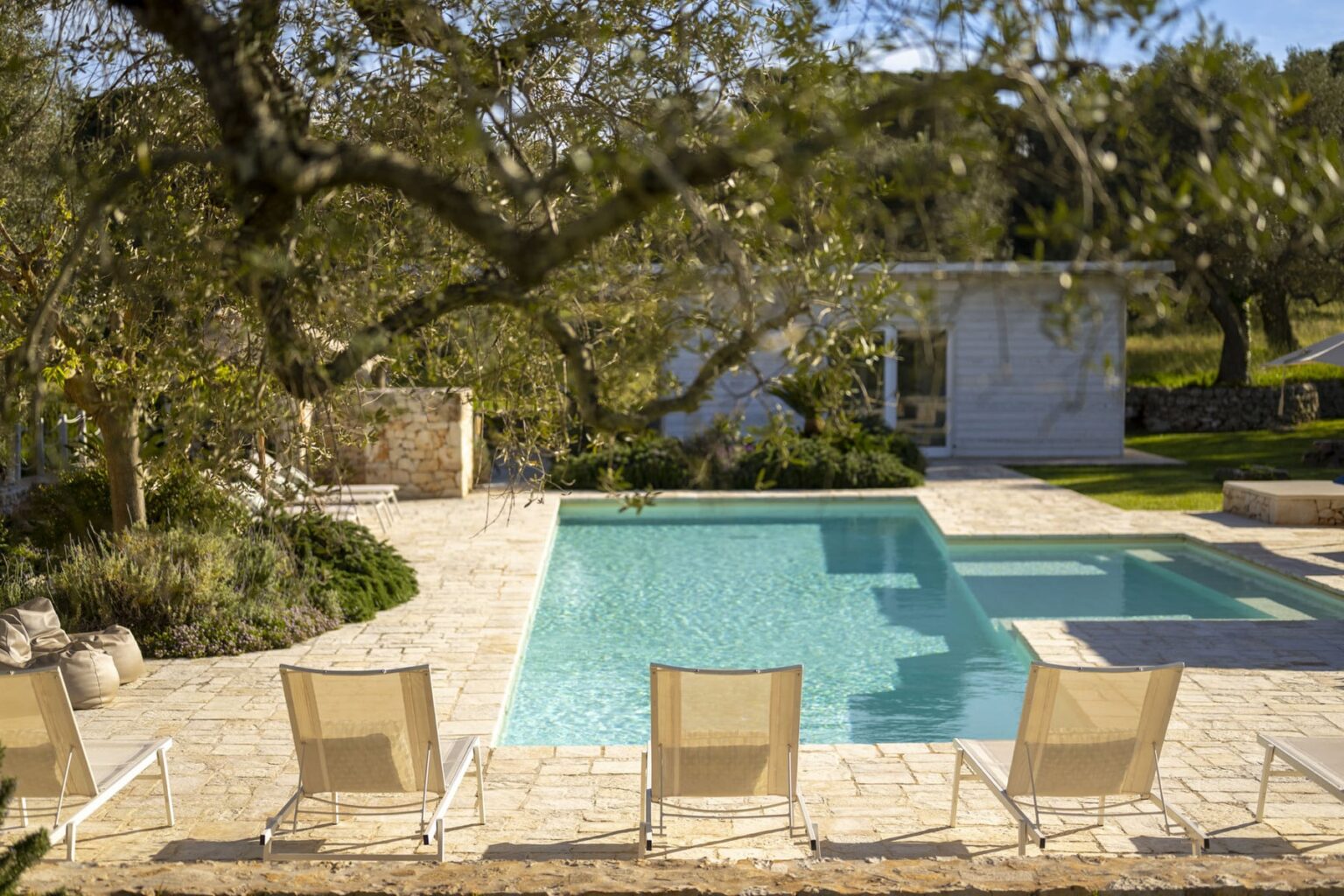 Serene outdoor swimming pool surrounded by lounge chairs and lush greenery, perfect for relaxation and leisure in a tranquil setting. | Only on SopranoVillas