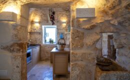 Rustic kitchen interior featuring natural stone walls, modern appliances, and warm lighting, creating a cozy atmosphere.