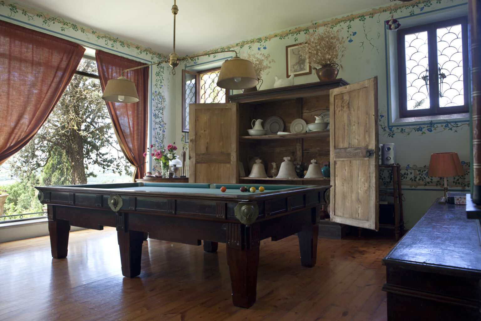 Interior view of a vintage game room featuring a classic billiard table, wooden furniture, and large windows with curtains, showcasing a cozy and inviting atmosphere. | Only on SopranoVillas