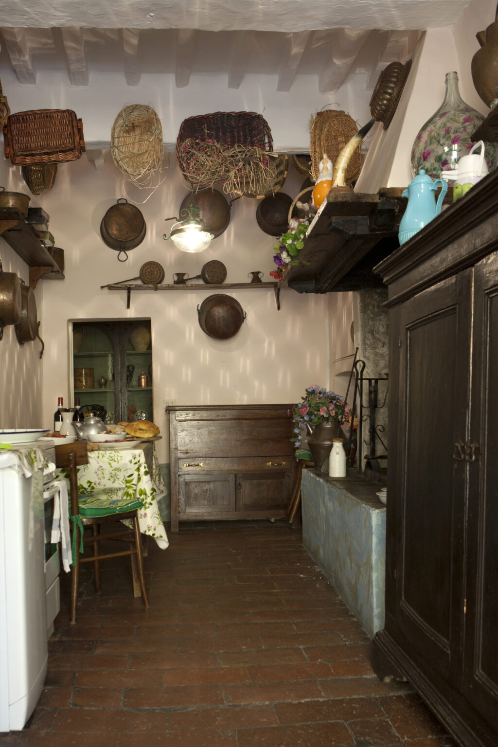 Charming rustic kitchen interior featuring wooden cabinets, vintage cookware hanging on the walls, and a cozy dining area with flowers. | Only on SopranoVillas