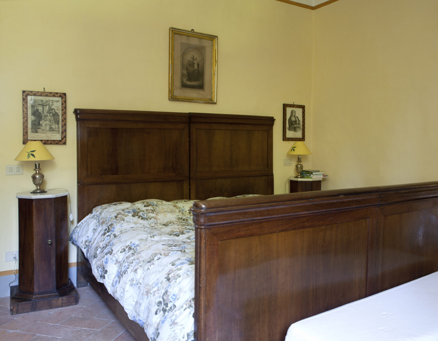Cozy bedroom featuring a wooden bed frame with a floral patterned quilt, side tables with lamps, and framed artwork on the walls, creating a warm and inviting atmosphere. | Only on SopranoVillas