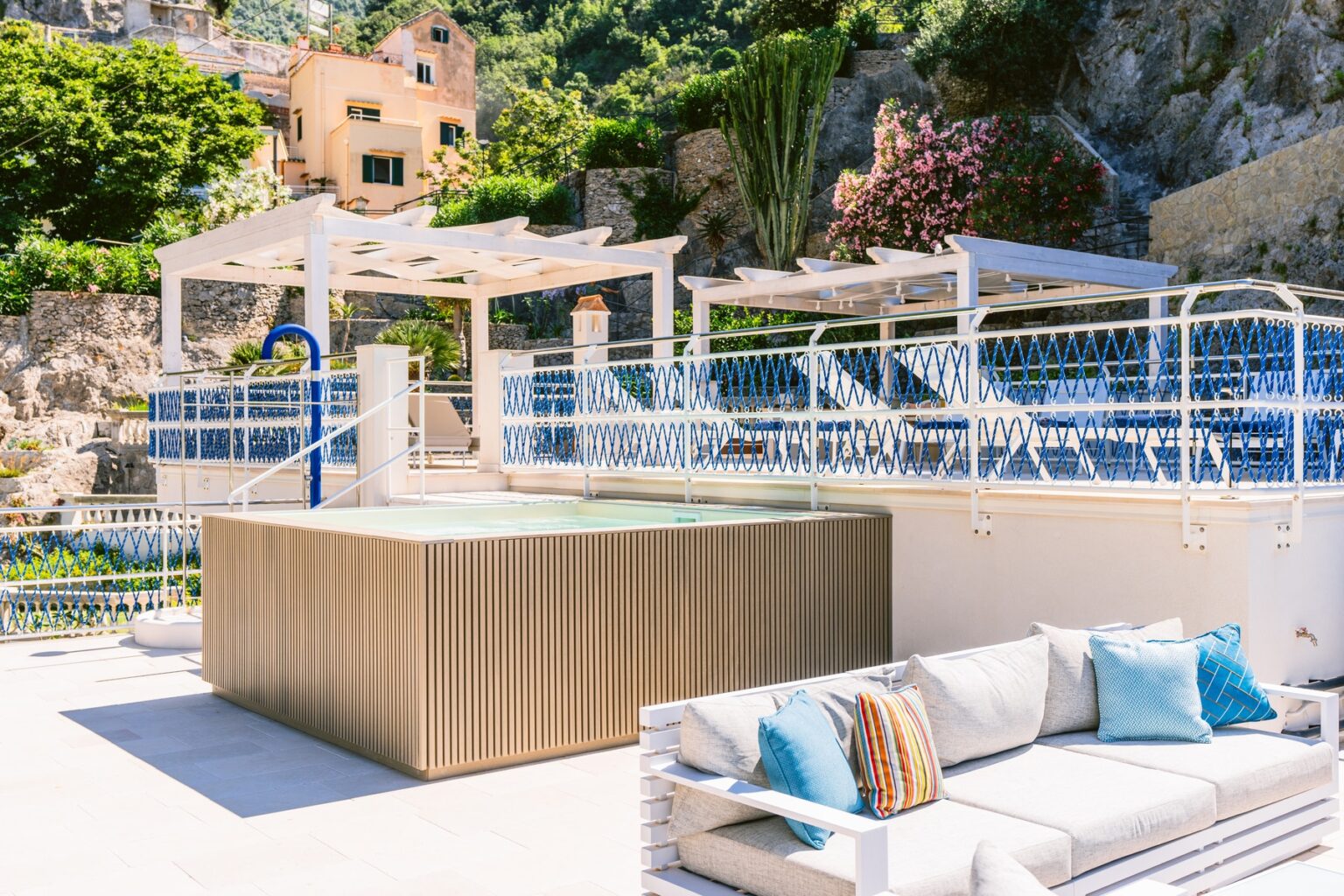Luxury outdoor terrace with a hot tub, comfortable seating, and stunning views of lush greenery and modern architecture. Ideal for relaxation and entertaining. | Only on SopranoVillas