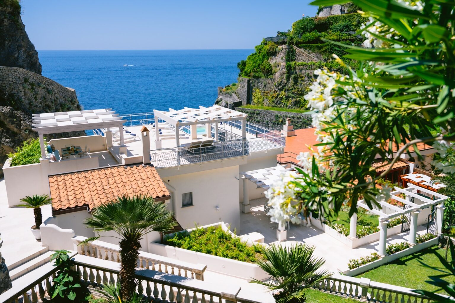 Luxury oceanfront villa with modern architecture, surrounded by lush greenery and stunning sea views. The property features an outdoor terrace, landscaped gardens, and a serene atmosphere ideal for relaxation. | Only on SopranoVillas