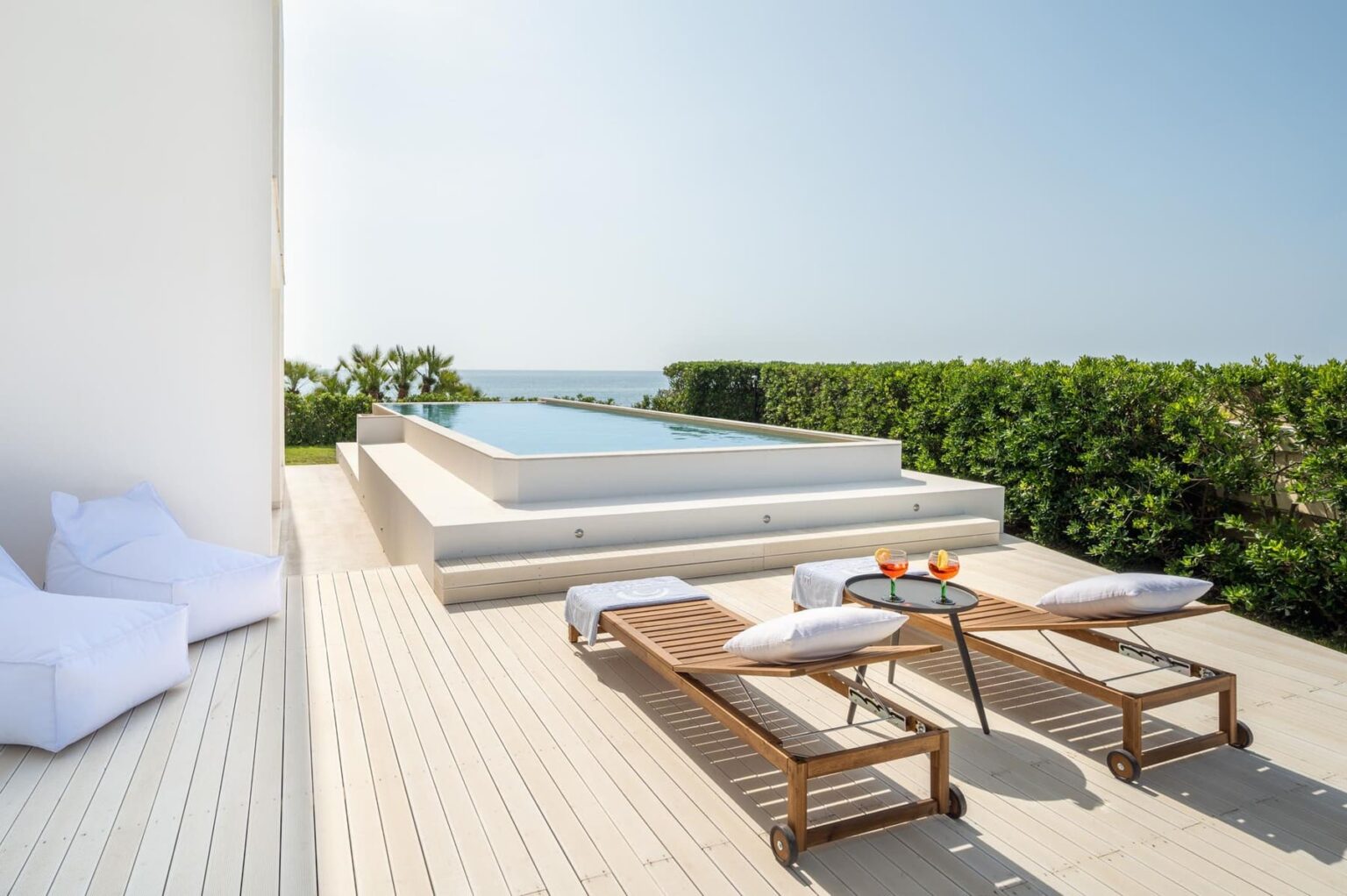 Modern outdoor terrace with a swimming pool, sun loungers, and a scenic ocean view, perfect for relaxation and leisure. | Only on SopranoVillas