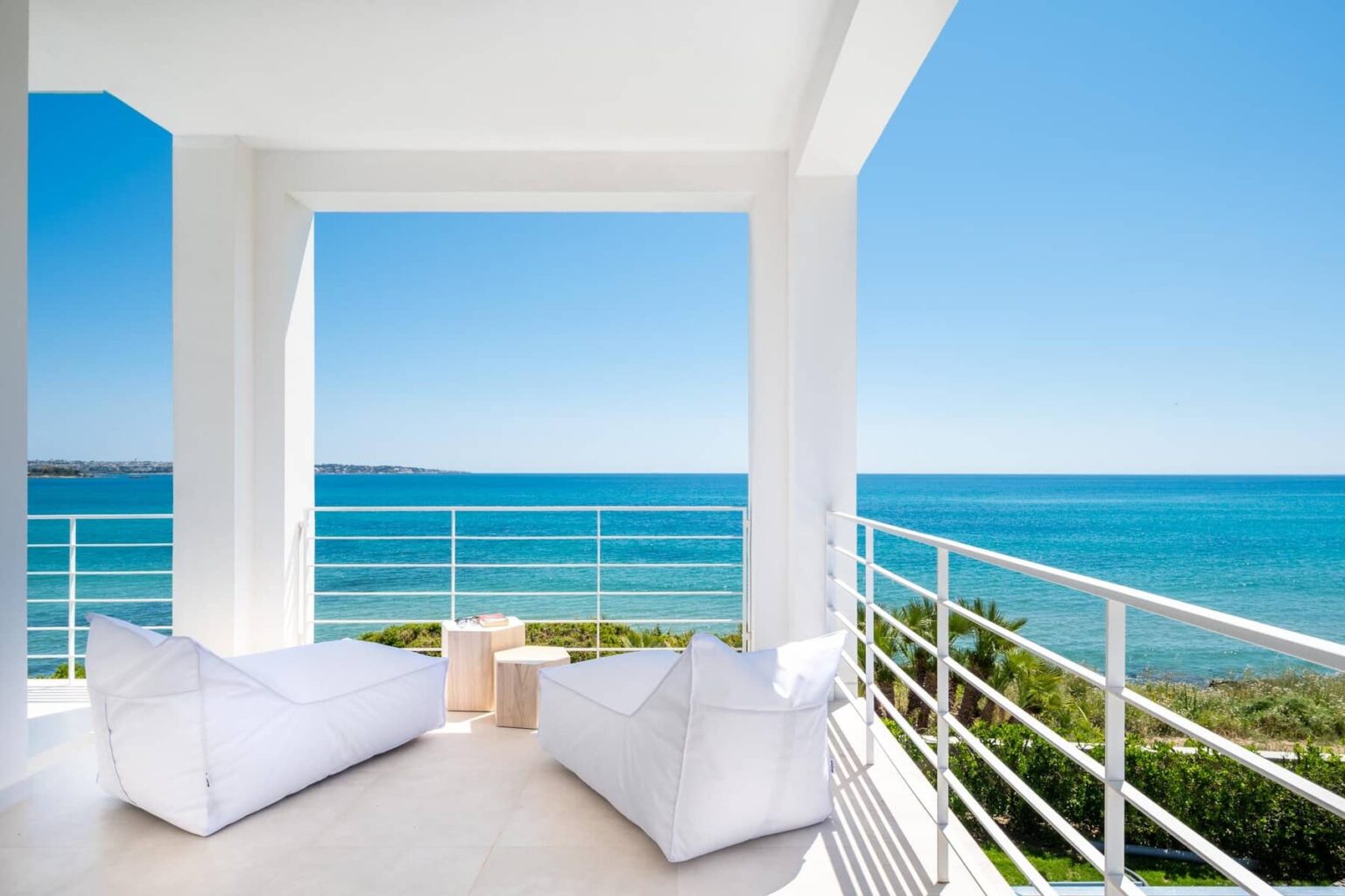 Modern beachfront balcony with white lounge chairs and ocean view, perfect for relaxation and enjoying coastal scenery. | Only on SopranoVillas