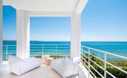 Modern beachfront balcony with white lounge chairs and ocean view, perfect for relaxation and enjoying coastal scenery.