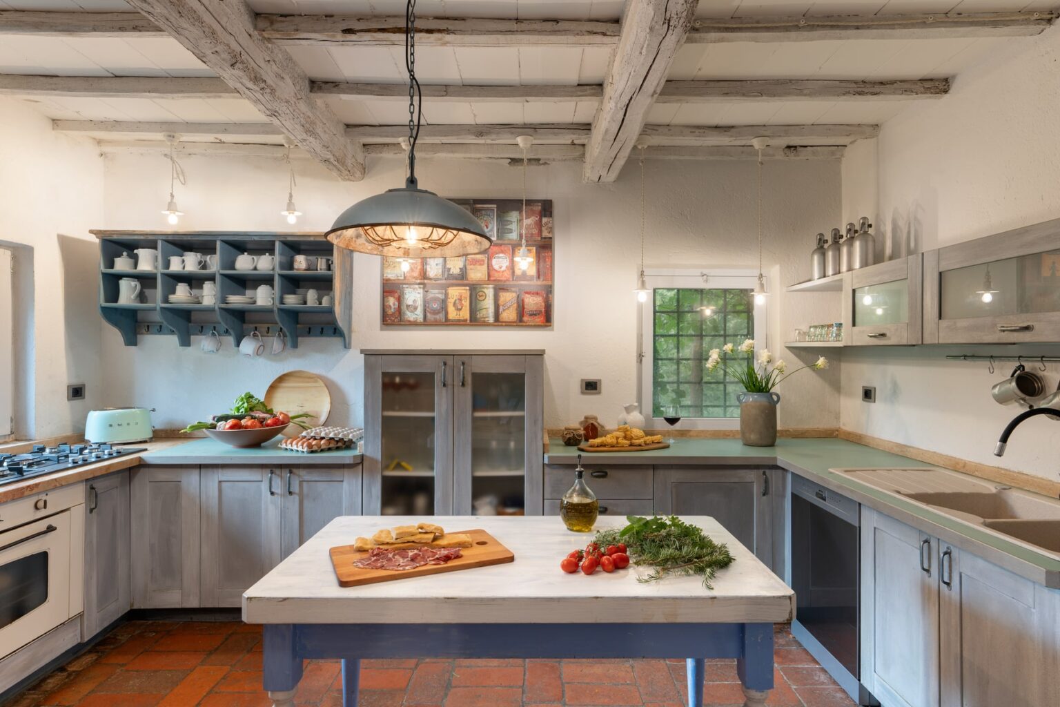 Spacious rustic kitchen with wooden beams, featuring a central island with fresh ingredients, modern appliances, and natural light from a window, creating an inviting cooking environment. | Only on SopranoVillas