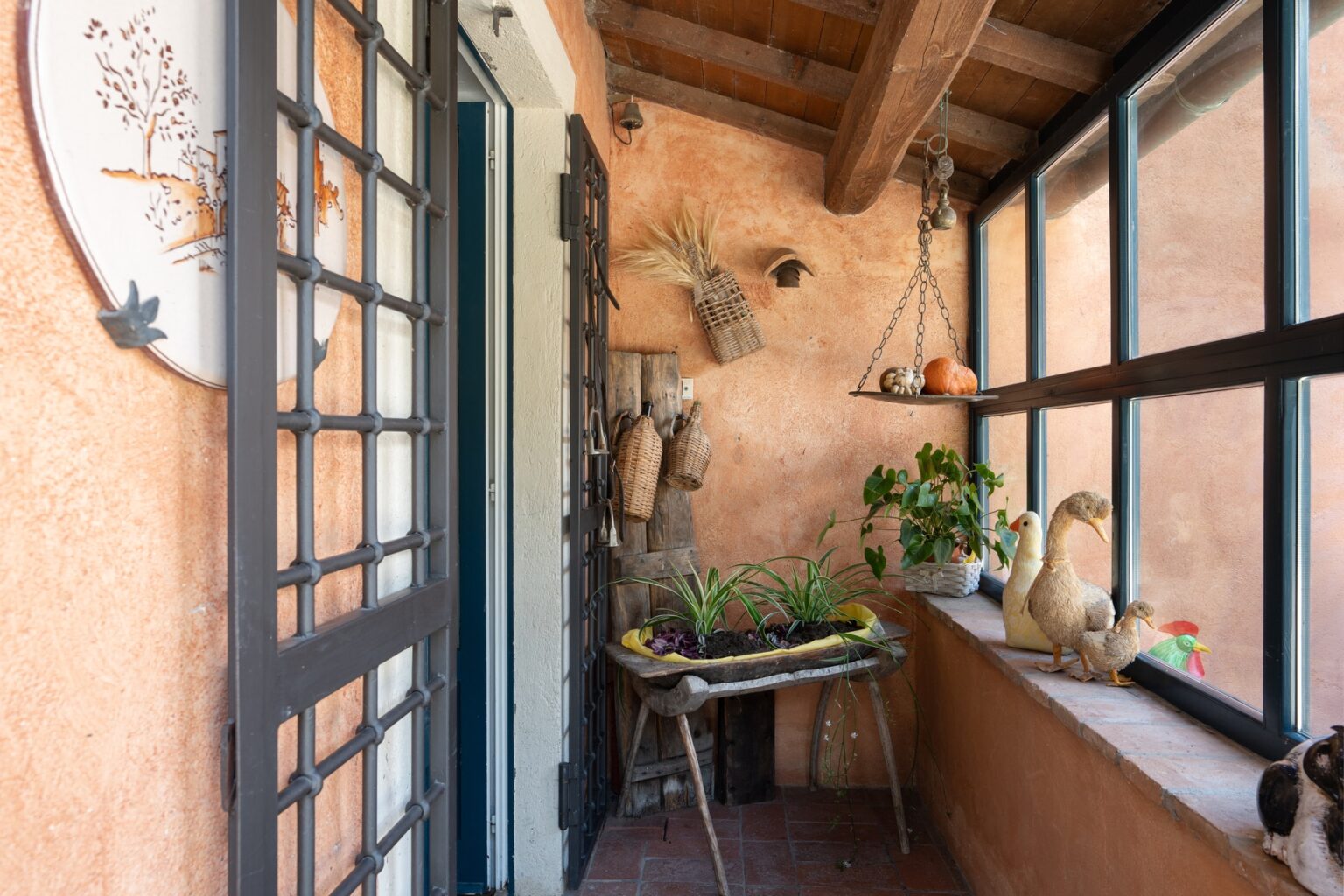 Cozy indoor balcony featuring a wooden ceiling, terracotta walls, potted plants, and decorative elements, creating a warm and inviting atmosphere. | Only on SopranoVillas