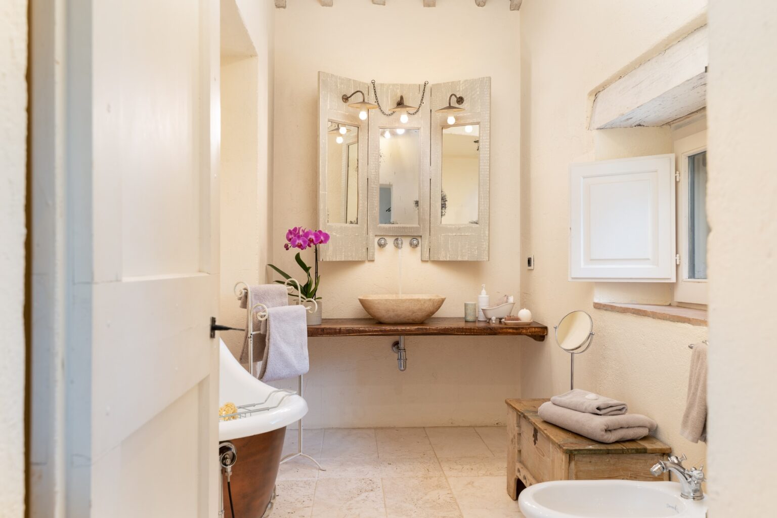 Modern bathroom interior featuring a wooden sink, elegant mirrors, and natural light. Decorated with a potted orchid and soft towels, this serene space combines functionality with aesthetic appeal. | Only on SopranoVillas