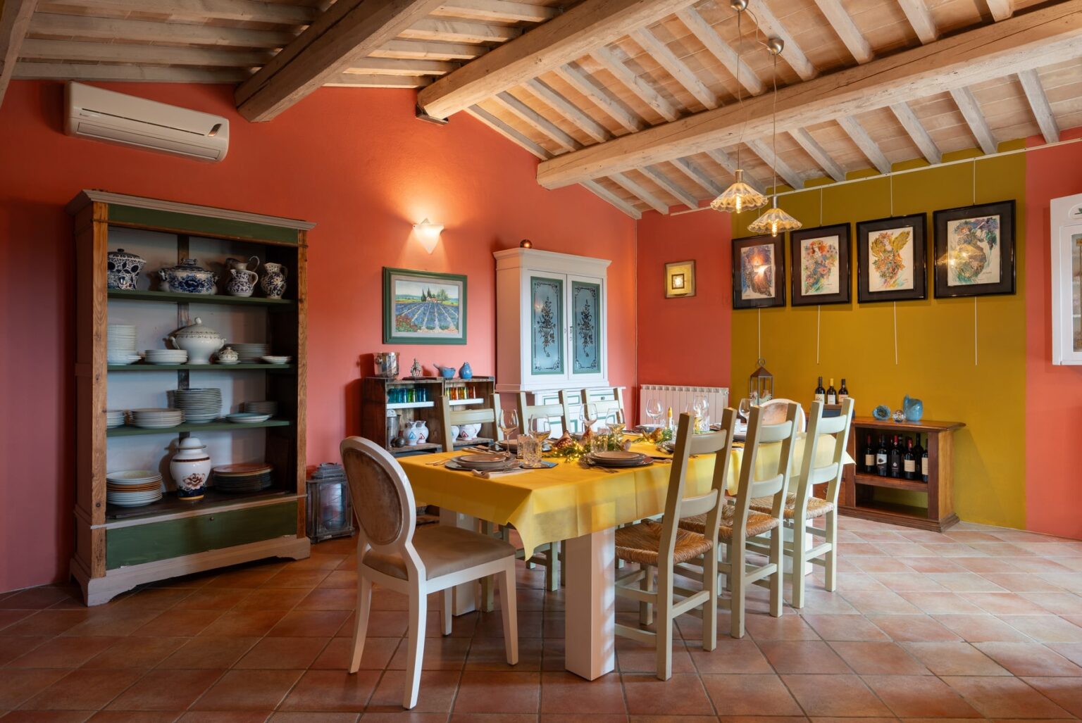 Cozy dining room featuring a large wooden table surrounded by chairs, vibrant red walls, and rustic decor, including a display cabinet and framed artwork, ideal for family gatherings and meals. | Only on SopranoVillas