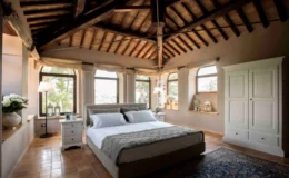 Spacious and elegantly designed bedroom featuring a king-size bed with plush bedding, wooden beams on the ceiling, large windows allowing natural light, and stylish decor elements including a bedside table and a white wardrobe.