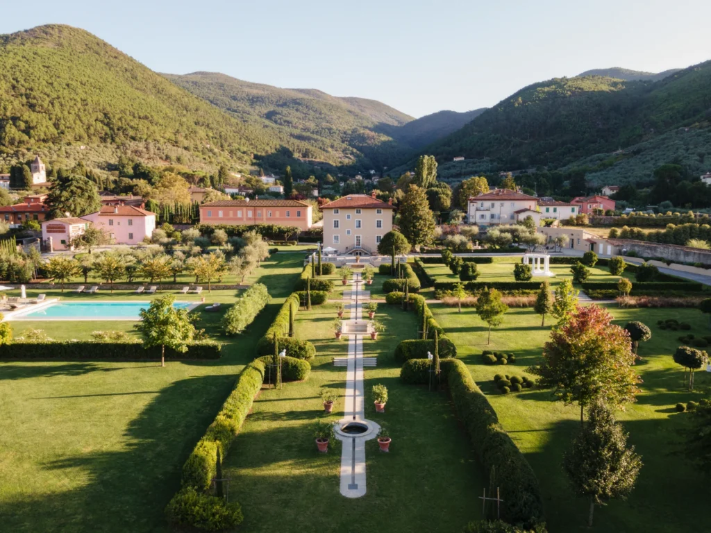 Aerial view of luxury villas for rent in Italy, featuring manicured gardens, a swimming pool, and scenic mountain backdrop. Ideal destination for relaxation and elegance. | Only on SopranoVillas