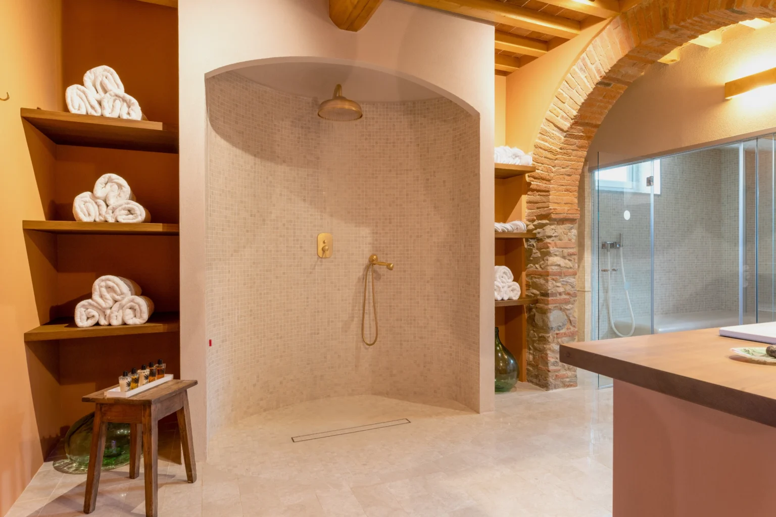 Luxurious bathroom in an Italian villa featuring a spacious walk-in shower, elegant stone finishes, and neatly arranged towels on shelves, ideal for a relaxing getaway. | Only on SopranoVillas