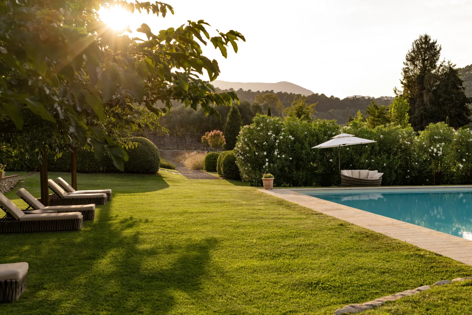 Luxury villa rental in Italy featuring a serene garden, inviting swimming pool, and comfortable lounge chairs, ideal for a relaxing getaway. | Only on SopranoVillas