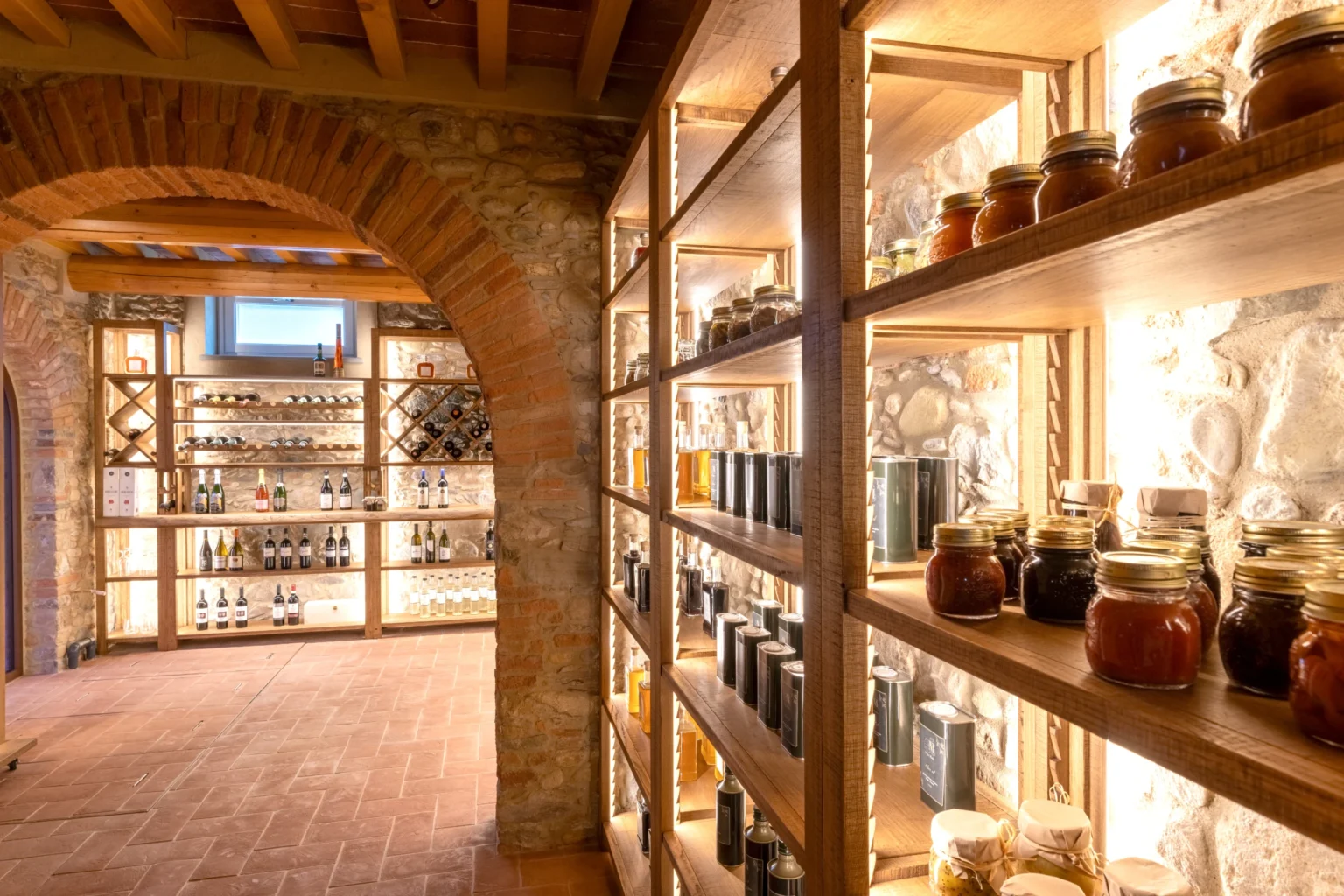 Interior view of a luxury villa in Italy featuring a beautifully designed pantry with wooden shelves displaying an array of gourmet jars and bottles, highlighting the villa's elegance and attention to detail. Perfect for discerning travelers seeking a unique rental experience. | Only on SopranoVillas