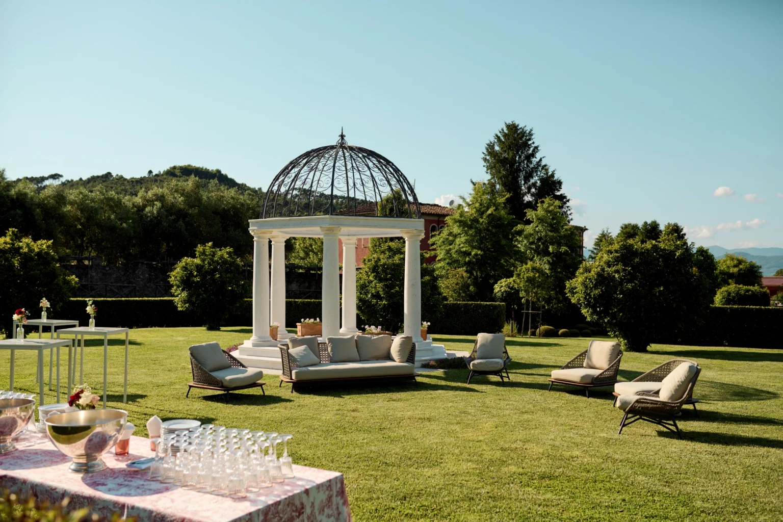 Luxury villa rental in Italy featuring an elegant outdoor gazebo surrounded by lush greenery and stylish lounge chairs, perfect for relaxing in a picturesque setting. | Only on SopranoVillas
