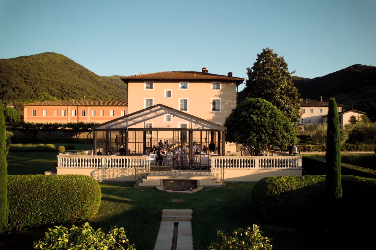 Luxury villa for rent in Italy featuring a spacious garden, elegant architecture, and stunning mountain views, perfect for a serene getaway. | Only on SopranoVillas