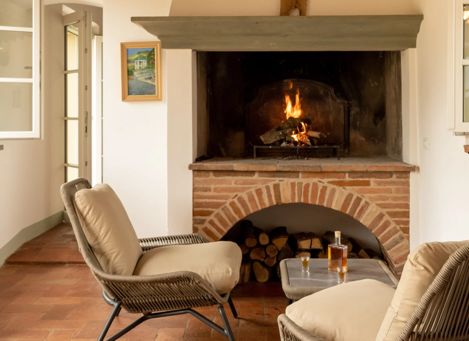 Cozy interior of a luxury villa in Italy featuring a brick fireplace, comfortable seating, and a warm ambiance, ideal for relaxation and vacation rental experiences. | Only on SopranoVillas