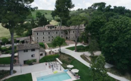 Aerial view of a luxurious stone villa surrounded by lush greenery, featuring a swimming pool and landscaped gardens, ideal for relaxation and outdoor activities.