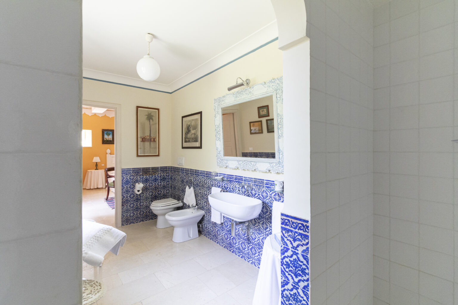 Bright and spacious bathroom featuring blue tiled accents, a large mirror, modern fixtures, and decorative artwork on the walls, creating a welcoming atmosphere. | Only on SopranoVillas