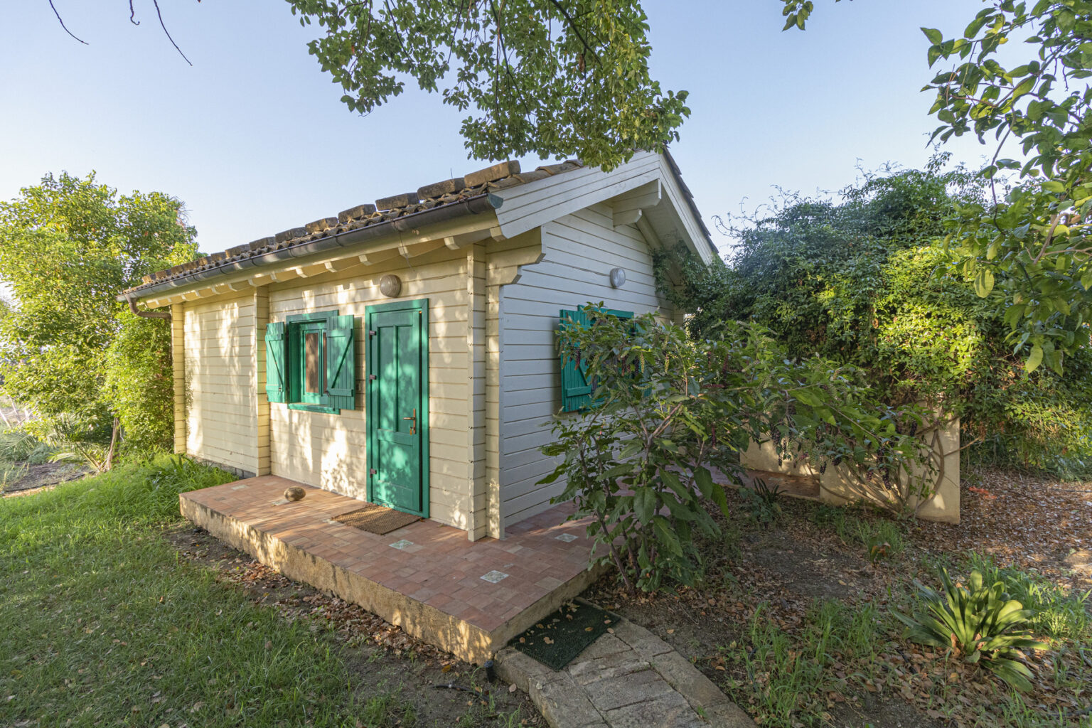 Charming small cottage with green shutters surrounded by lush greenery, offering a serene outdoor setting. Ideal for nature lovers and peaceful retreats. | Only on SopranoVillas