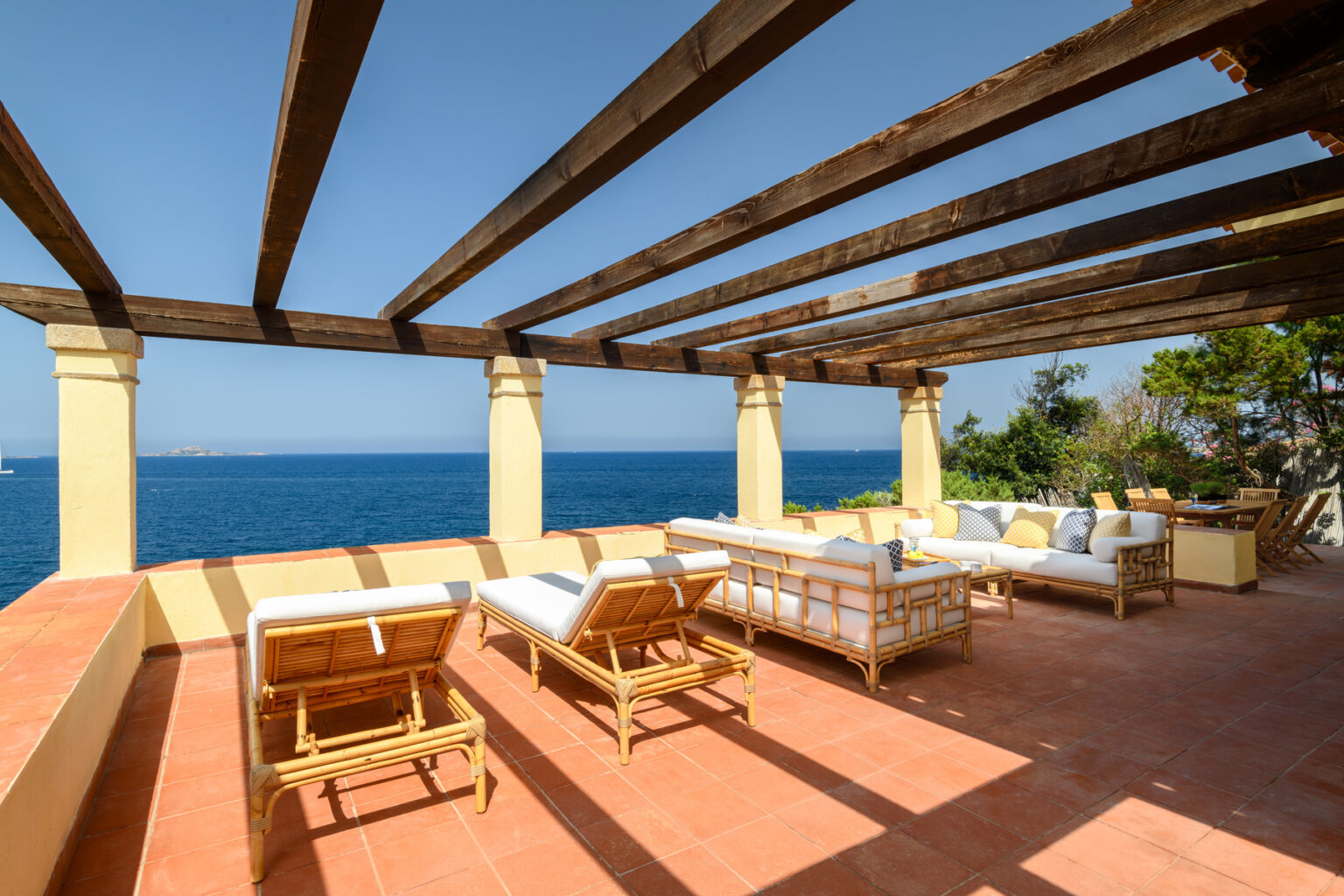 Stylish outdoor terrace with wooden beams and comfortable seating, overlooking a serene ocean view on a sunny day. Perfect for relaxation and entertaining. | Only on SopranoVillas