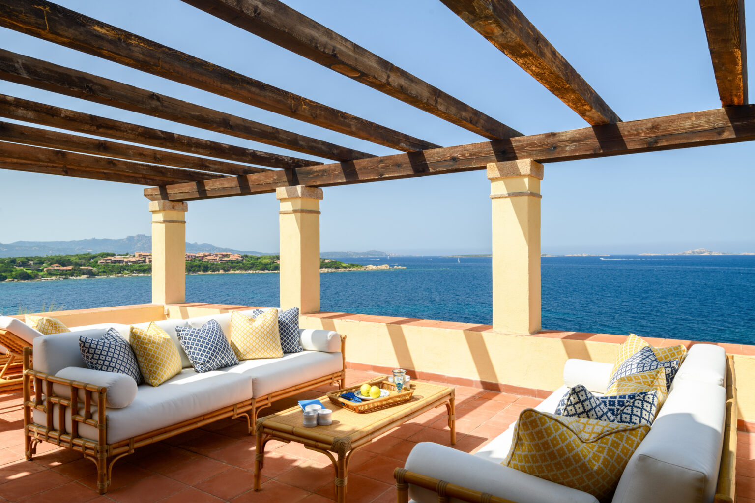 Cozy outdoor terrace with comfortable seating and ocean view, featuring a wooden pergola and decorative cushions, ideal for relaxation and entertaining. | Only on SopranoVillas