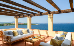 Cozy outdoor terrace with comfortable seating and ocean view, featuring a wooden pergola and decorative cushions, ideal for relaxation and entertaining.