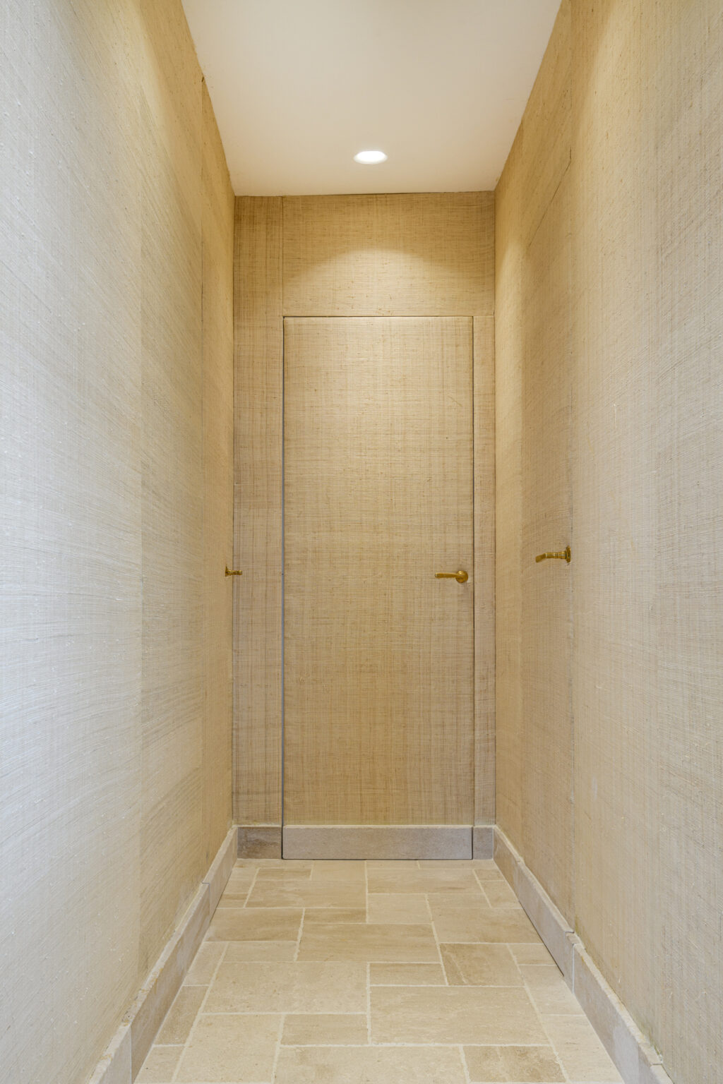 Interior view of a modern hallway featuring textured walls and two minimalist doors with gold handles, illuminated by soft lighting. | Only on SopranoVillas