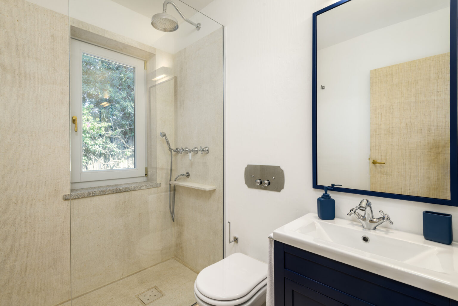 Modern bathroom design featuring a walk-in shower, sleek vanity with a mirror, and natural light from a window. The neutral color palette and contemporary fixtures create a stylish and functional space. | Only on SopranoVillas