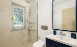 Modern bathroom design featuring a walk-in shower, sleek vanity with a mirror, and natural light from a window. The neutral color palette and contemporary fixtures create a stylish and functional space.