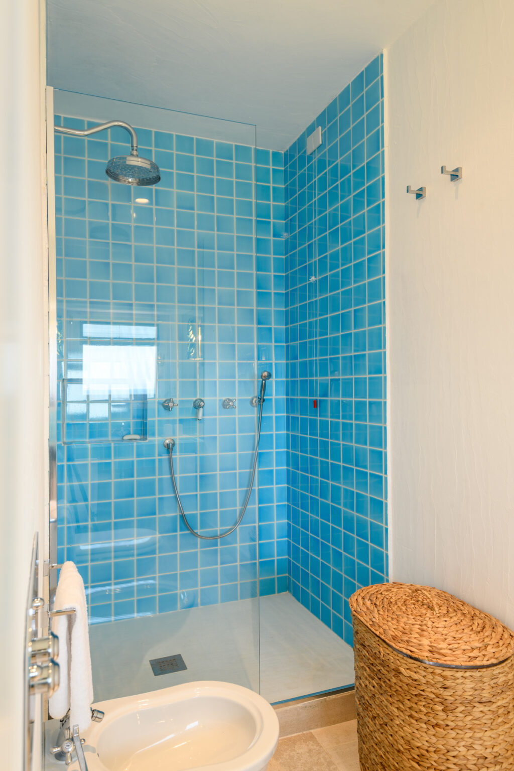 Modern shower enclosure with vibrant blue tiled walls, featuring a sleek showerhead and controls, perfect for a refreshing bathroom upgrade. | Only on SopranoVillas