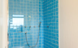Modern shower enclosure with vibrant blue tiled walls, featuring a sleek showerhead and controls, perfect for a refreshing bathroom upgrade.