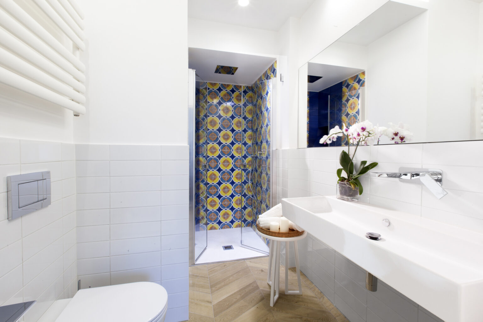 Modern bathroom featuring a sleek white sink, a stylish shower with a vibrant patterned curtain, and decorative plants. The interior design combines functionality with aesthetic appeal, showcasing a blend of light colors and contemporary fixtures. | Only on SopranoVillas