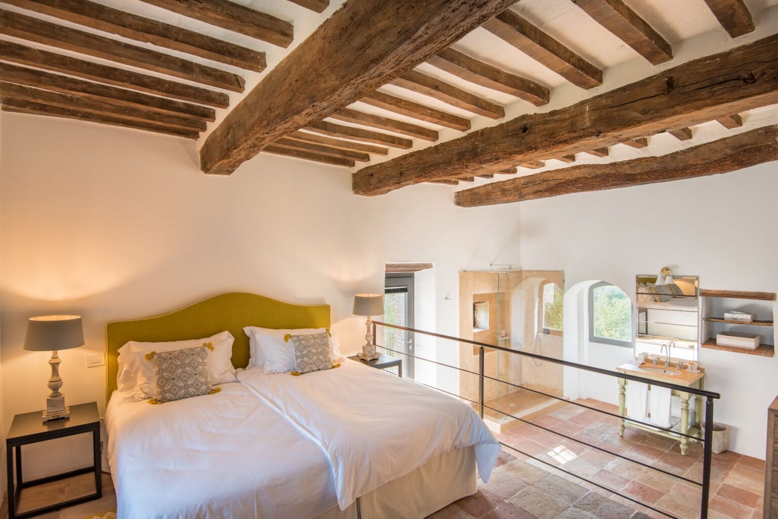 Spacious and stylish bedroom with a green upholstered headboard, two twin beds, wooden beams, and modern bathroom features, perfect for a cozy retreat. | Only on SopranoVillas