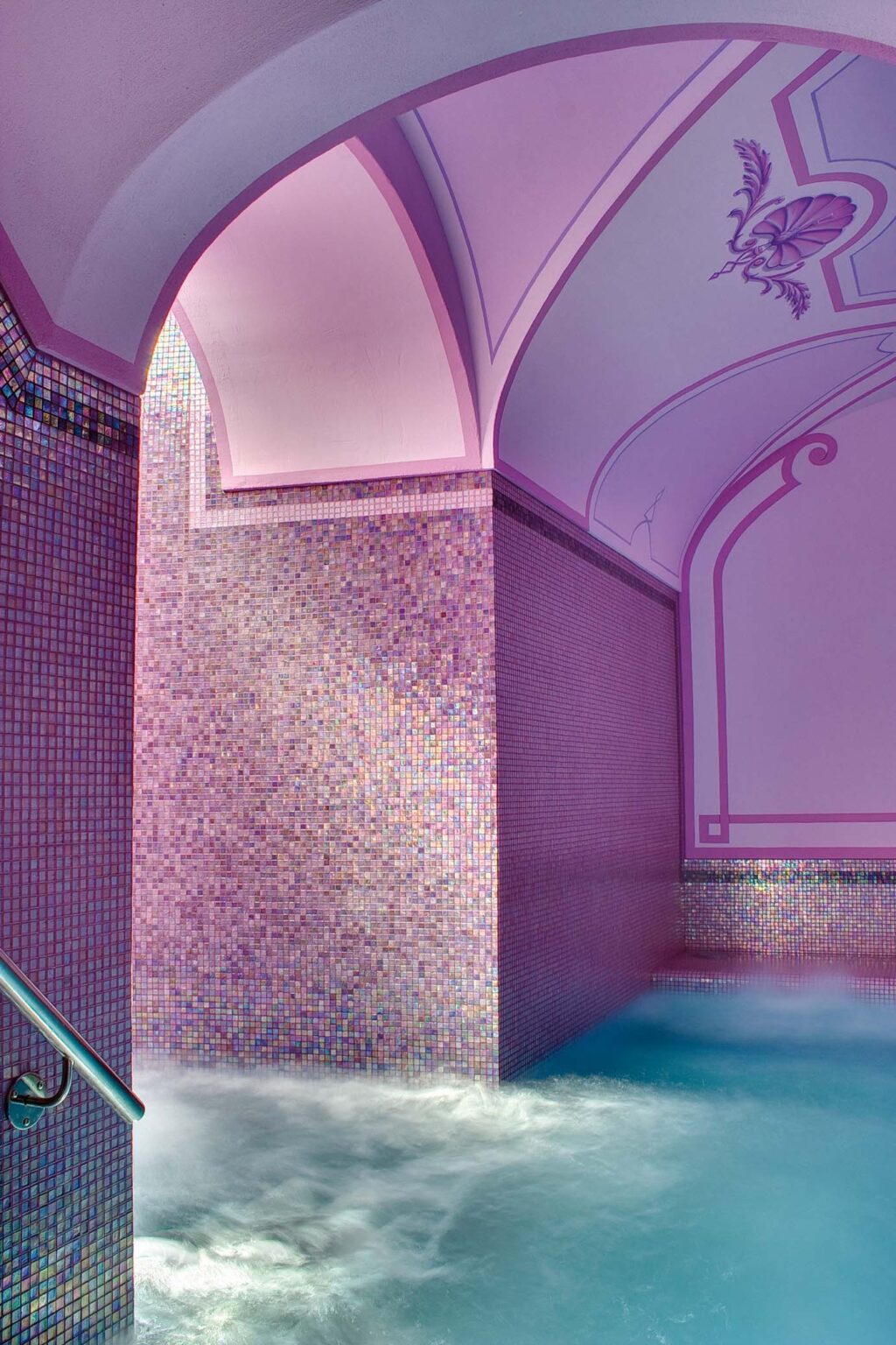 Serene spa interior featuring a relaxing water feature surrounded by colorful mosaic tiles and softly lit arches, creating an inviting atmosphere for wellness and relaxation. | Only on SopranoVillas