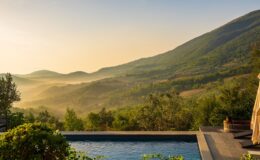 Serene mountain landscape at sunrise featuring lush greenery, rolling hills, and a tranquil swimming pool, perfect for relaxation and outdoor retreats.
