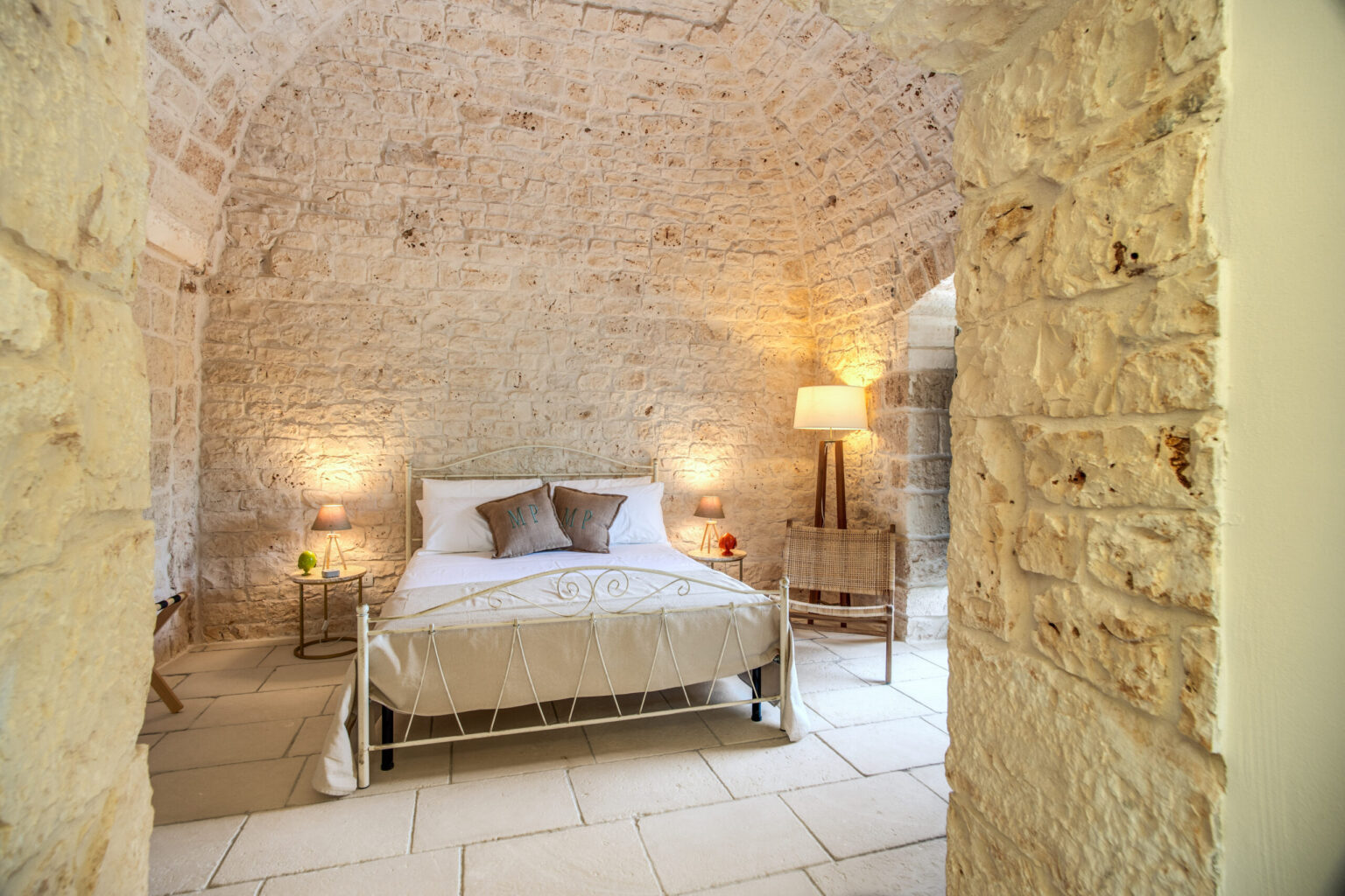 Cozy bedroom with a stone arch ceiling, featuring a comfortable bed, decorative pillows, and warm lighting from bedside lamps, creating a serene atmosphere. | Only on SopranoVillas