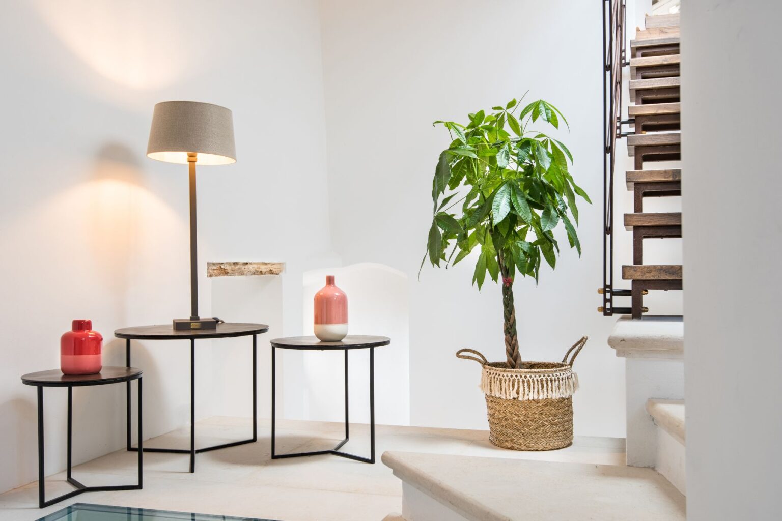 Modern interior design featuring a stylish lamp, decorative vases, and a lush potted plant in a well-lit staircase area. The scene showcases minimalist furniture with a blend of natural and contemporary elements, creating an inviting atmosphere. | Only on SopranoVillas