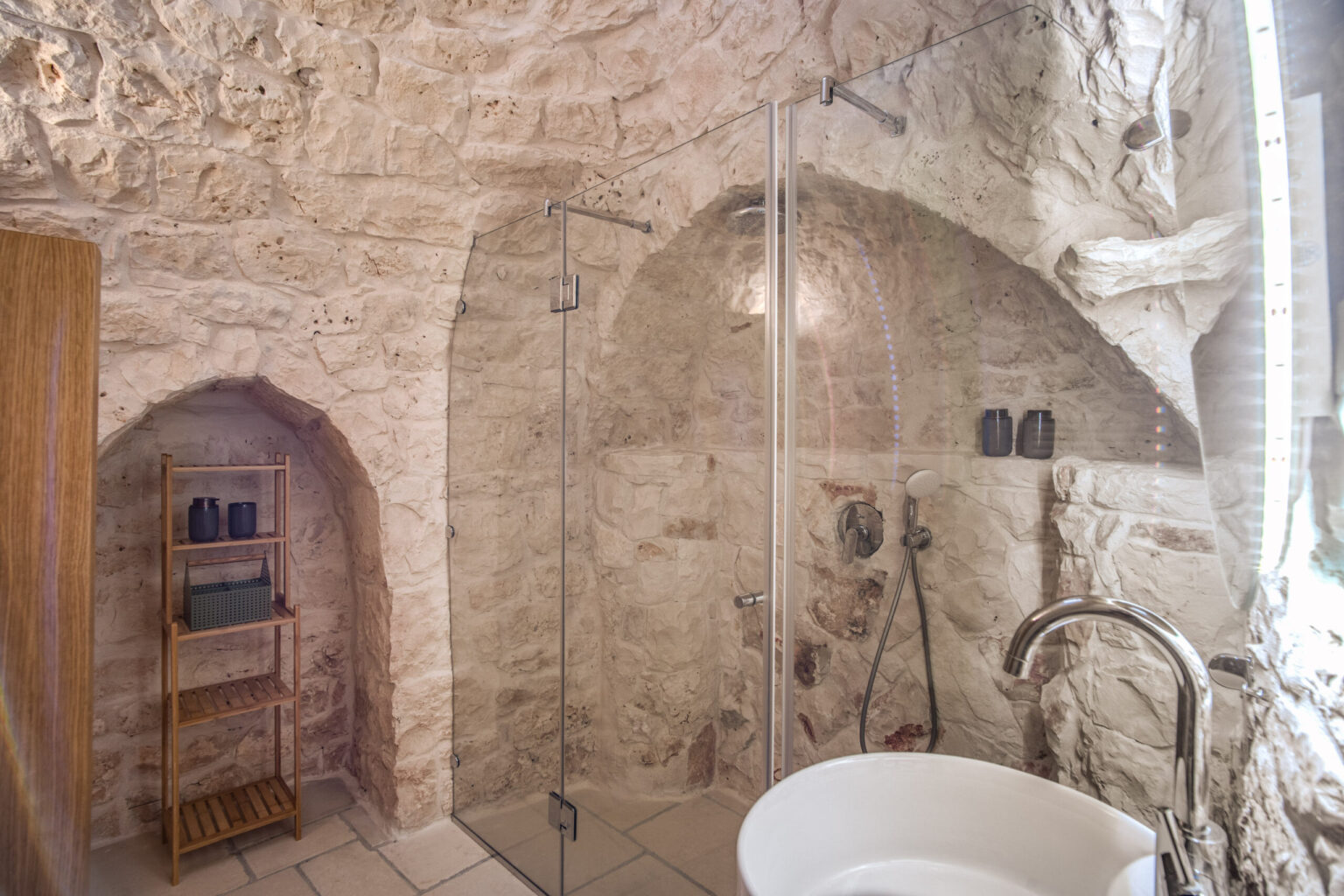 Modern bathroom featuring natural stone walls, a glass shower enclosure, and a freestanding bathtub, designed with minimalist decor and earthy tones. | Only on SopranoVillas