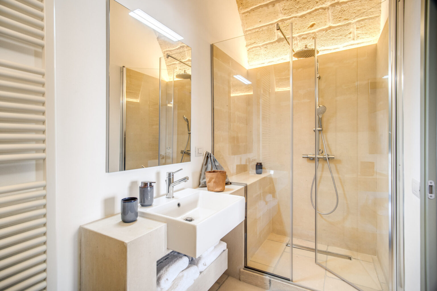 Modern bathroom interior featuring a glass shower, sleek vanity with sink, and contemporary mirrors, complemented by warm lighting and neutral tile design. | Only on SopranoVillas