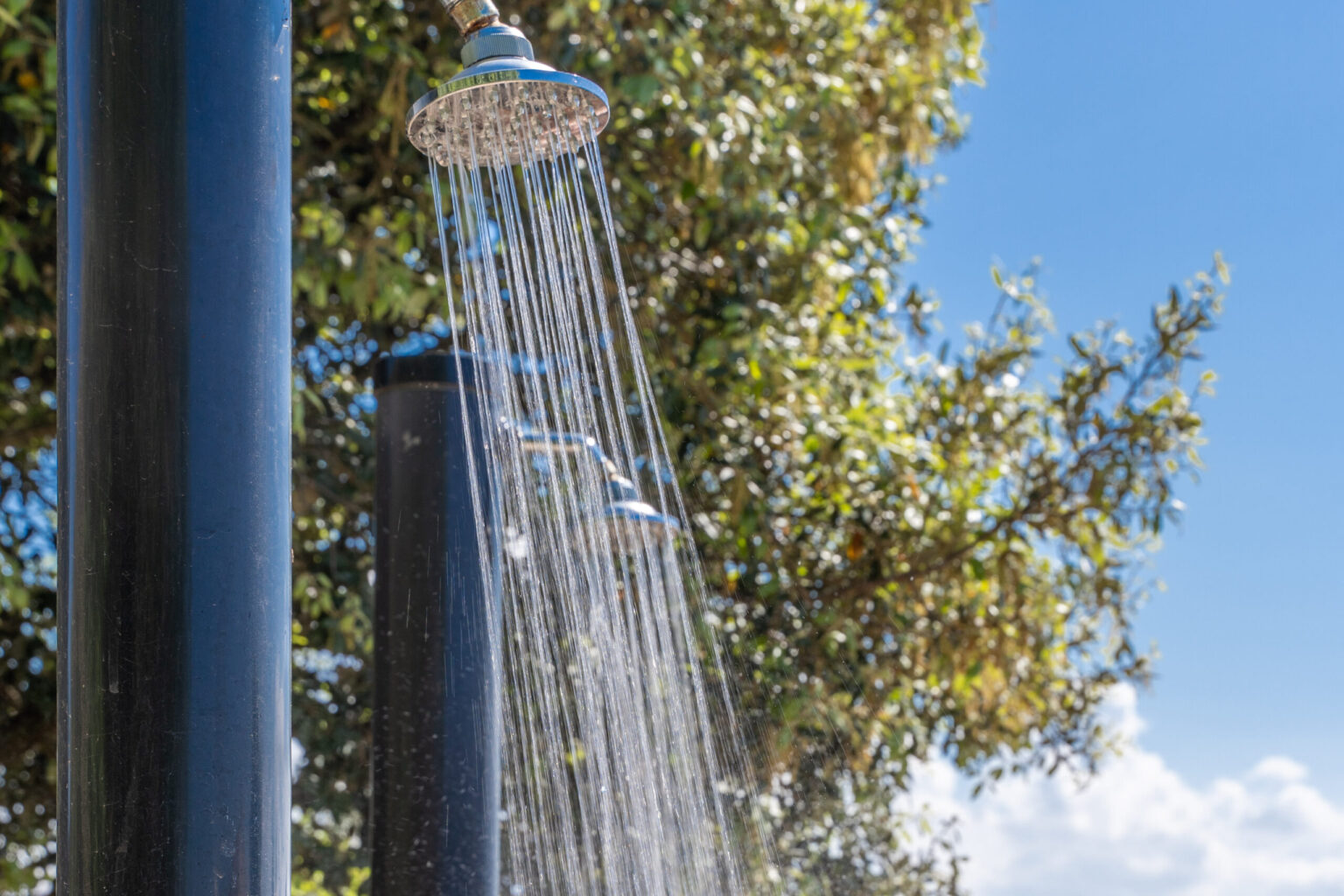 Outdoor shower with flowing water, surrounded by greenery and blue sky, ideal for refreshing outdoor experiences. | Only on SopranoVillas