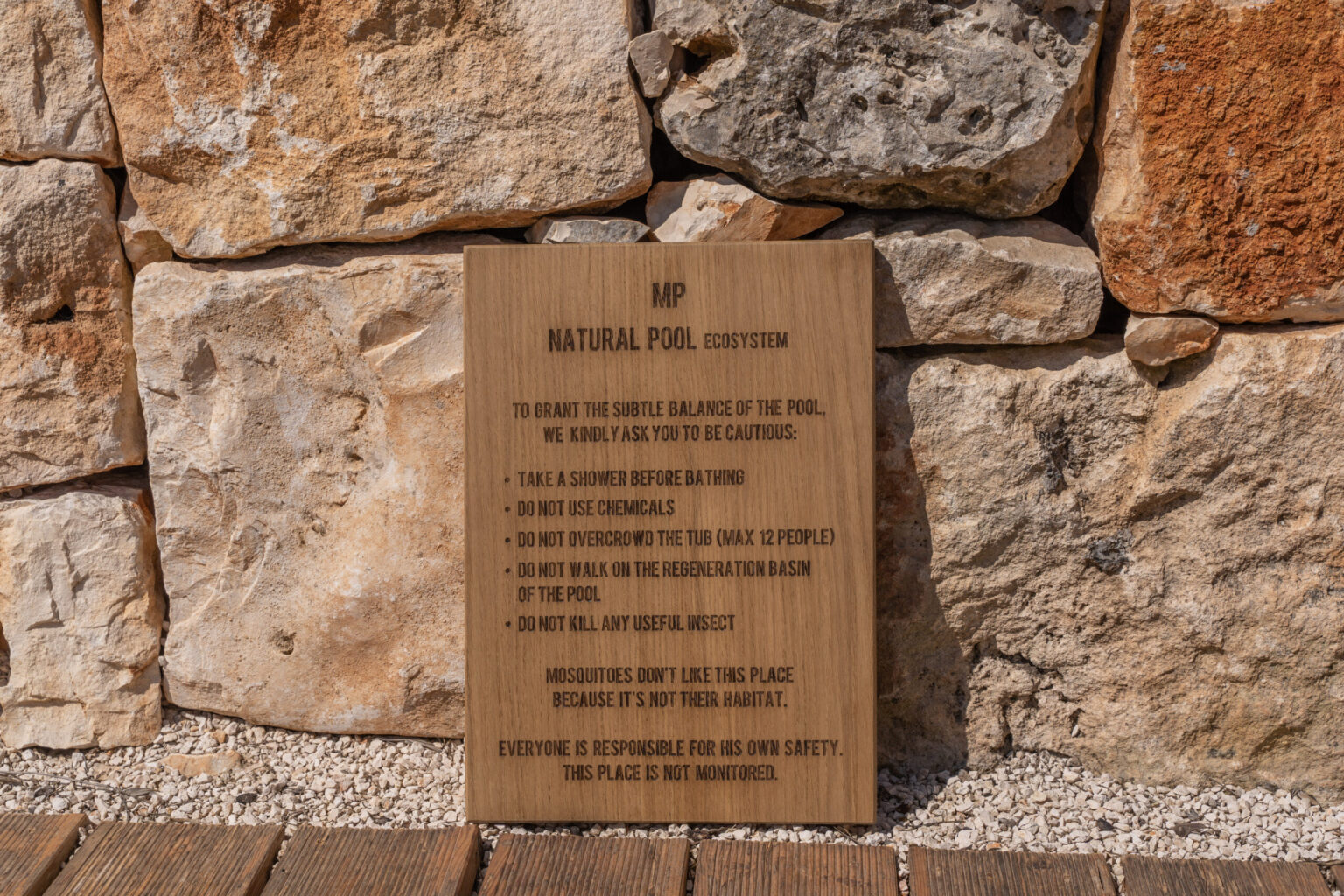 Wooden plaque displaying information about a national park, mounted on a stone wall. The plaque includes guidelines and rules for visitors, emphasizing conservation and safety. Natural stone background enhances the rustic setting. | Only on SopranoVillas