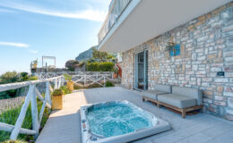 Cozy outdoor patio with a hot tub and comfortable seating, featuring a stunning view of the landscape and clear blue sky. Perfect for relaxation and leisure activities.