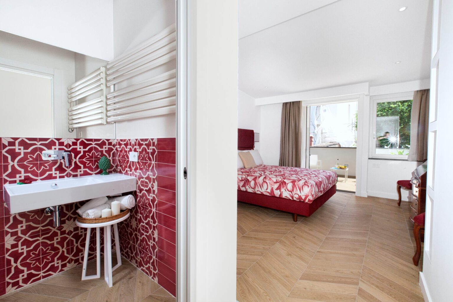 Modern hotel room with a red-themed bedroom and stylish bathroom. The spacious layout features a wooden floor, large windows, and contemporary decor, offering a bright and inviting atmosphere. | Only on SopranoVillas