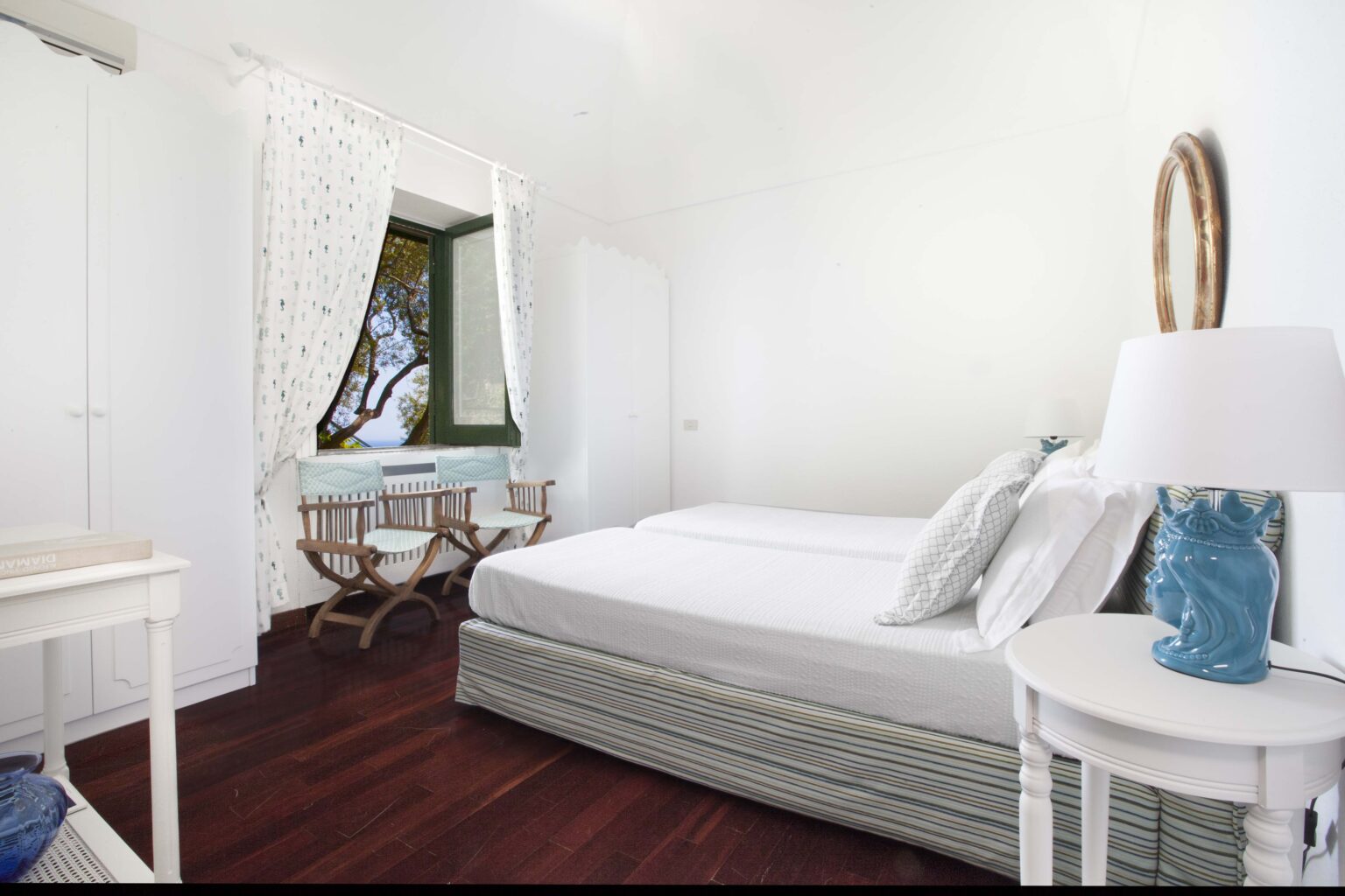 Luxurious bedroom in a rental villa in Italy, featuring a comfortable bed, elegant decor, and large window with scenic views, perfect for a relaxing getaway. | Only on SopranoVillas