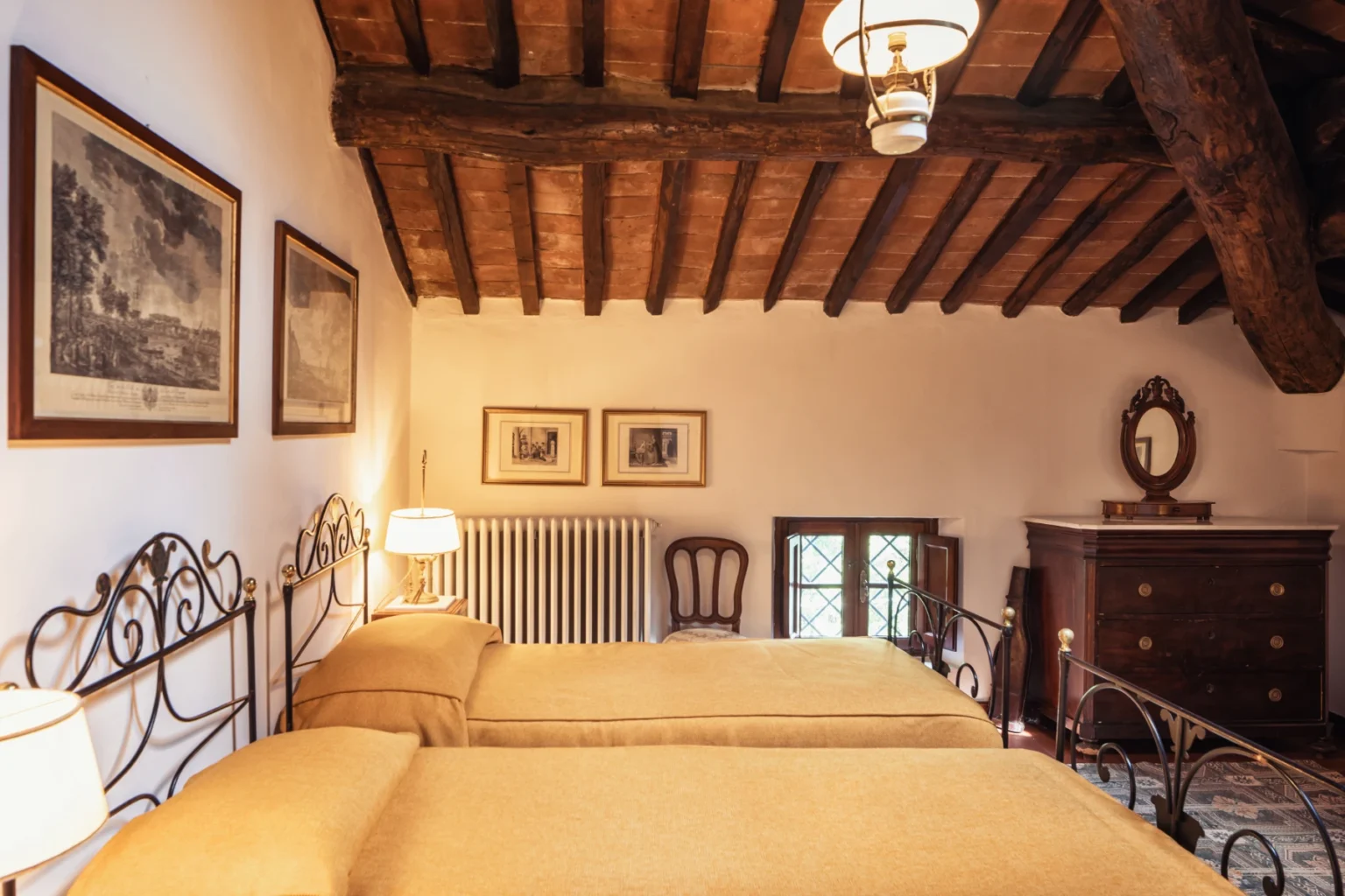 Cozy bedroom featuring two twin beds with yellow bedding, wooden beam ceiling, vintage artwork on the walls, and a charming dresser, creating a warm and inviting atmosphere. | Only on SopranoVillas