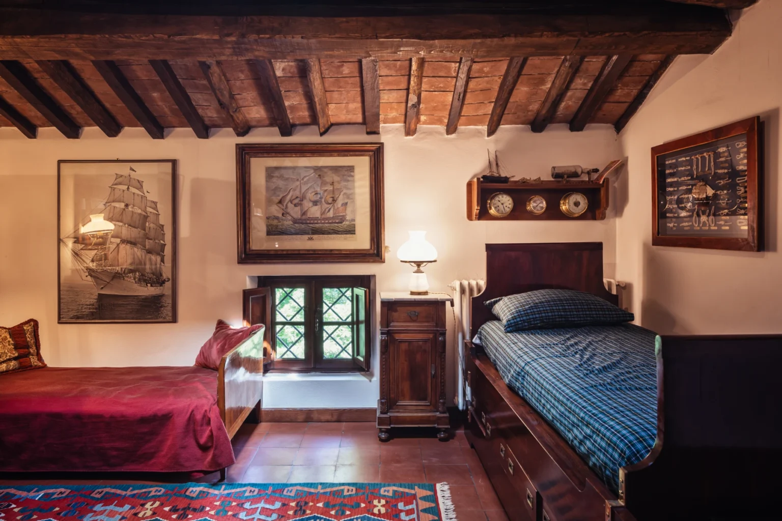 Cozy rustic bedroom featuring wooden beams, two beds with decorative bedding, vintage artwork, and a charming window with green shutters, creating a warm and inviting atmosphere. | Only on SopranoVillas